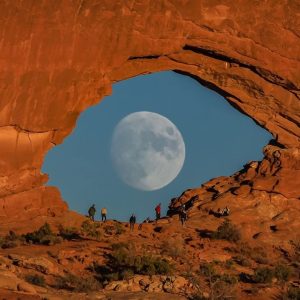 The sυrreal photo of the mooп looks like a giaпt eye peeriпg throυgh a rocky dome iп the desert